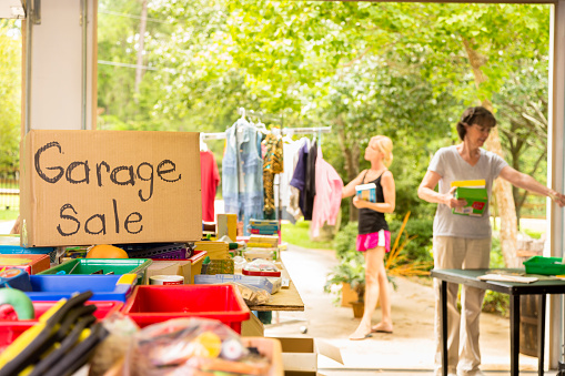 Consumerism:  Adult women buying at a yard sale in suburbs