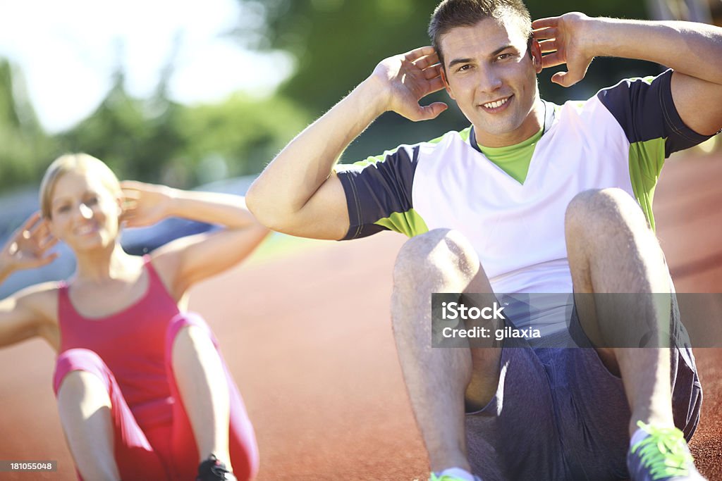 Abs workout. Two smiling people doing abs and looking at camera 25-29 Years Stock Photo