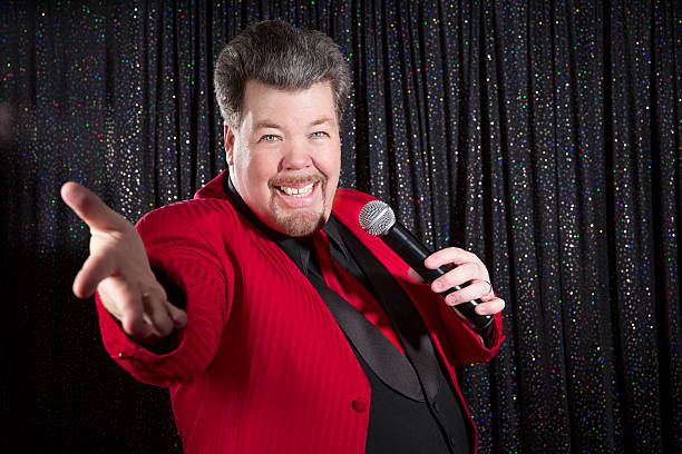 istock Welcoming well dressed middle-aged man with microphone on stage 181055143