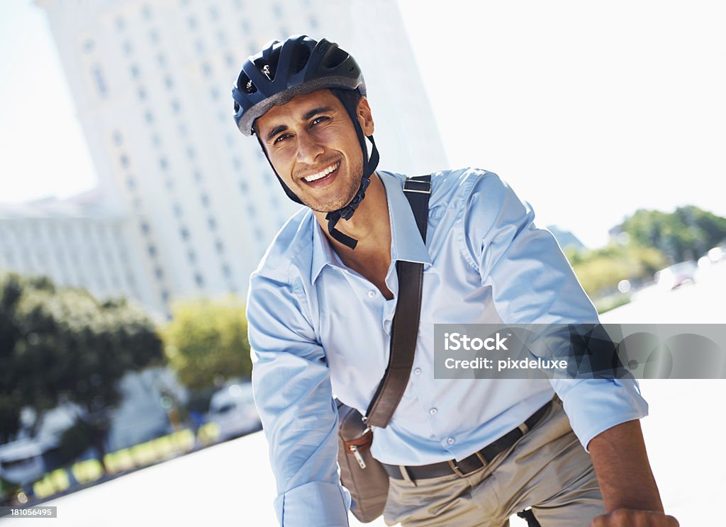 Keeping the environment in mind A young businessman riding to work on a bicycle Helmet Stock Photo