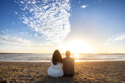 Couple on the beach at sunset - sitting together