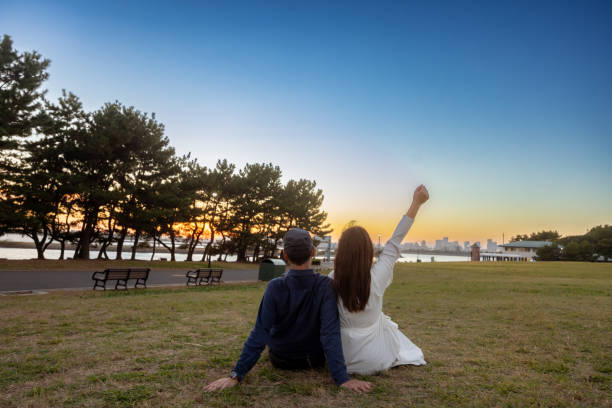 Couple sitting together on grass in seaside park at sunset time