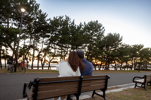 Couple sitting on bench at sunset time