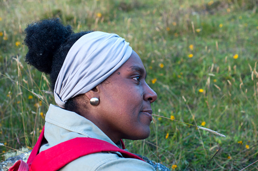 afro woman resting among mountain flowers after traveling on a mountain trail