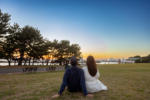 Couple sitting together on grass in seaside park at sunset time