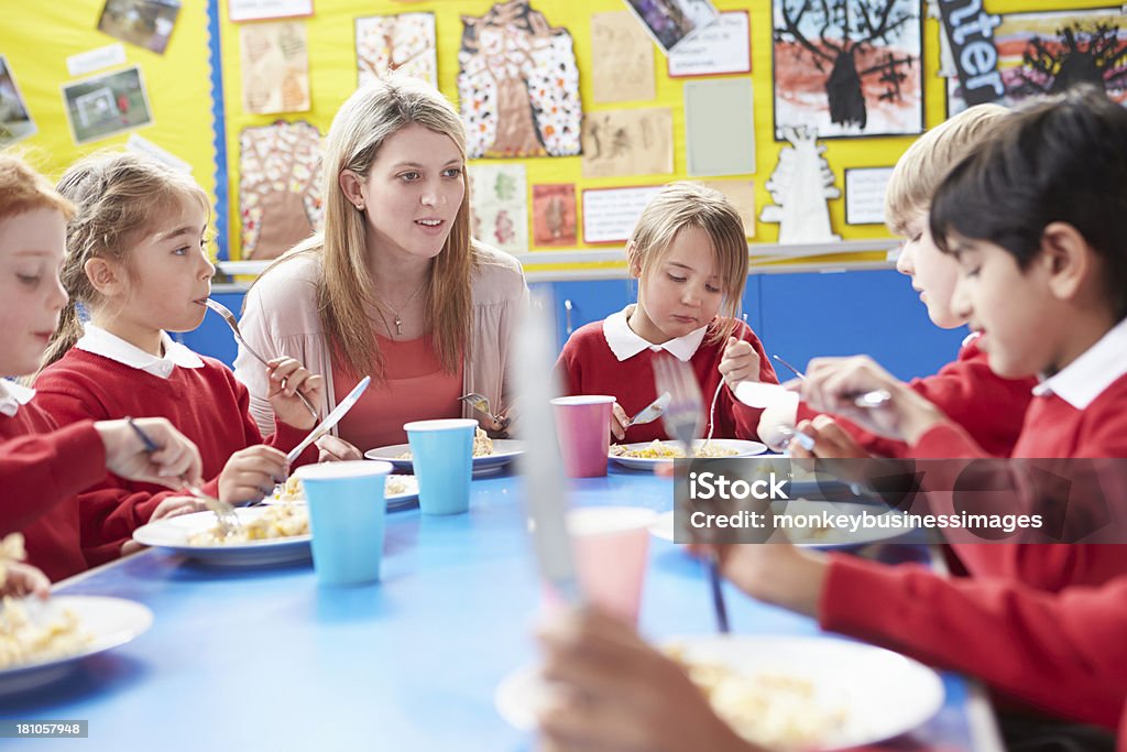 Alunos com o professor sentado à mesa - Foto de stock de Almoço royalty-free