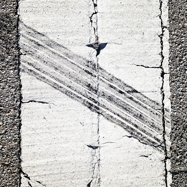 Skid tire tread track across a white painted line on an asphalt road.