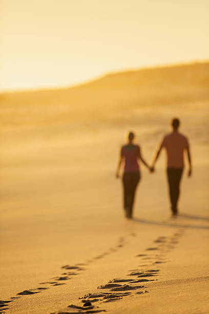 istock Couple Leaving Behind Track Of Footprints While Walking On Beach 181058548