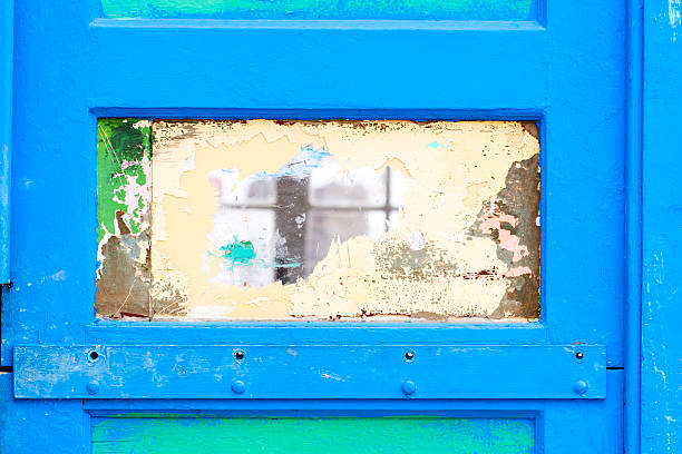 Weathered blue door with a painted, chipped glass window.