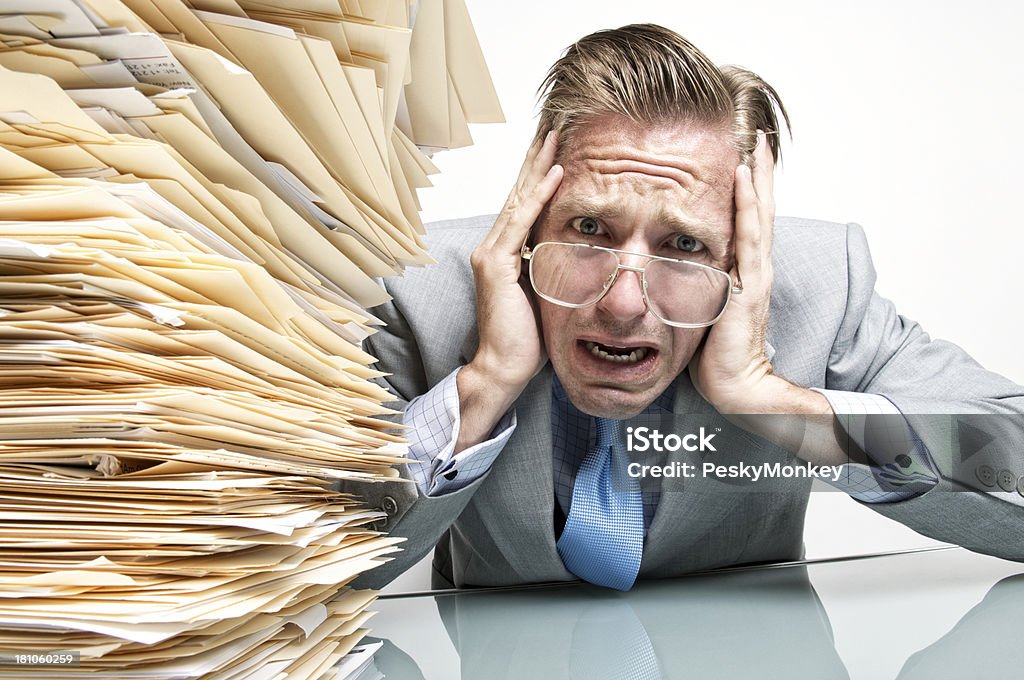 Businessman Crying from Stress at His Overflowing Inbox Businessman office worker sitting at his desk next to an overflowing inbox crying at the camera with an overwhelmed expression Document Stock Photo