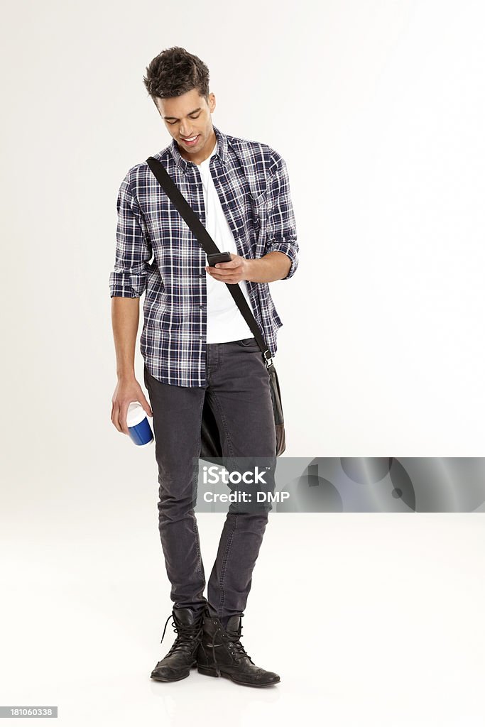 Young casual man texting on the phone Full length portrait of young casual man texting on the phone and holding a cup of coffee over white background Full Length Stock Photo