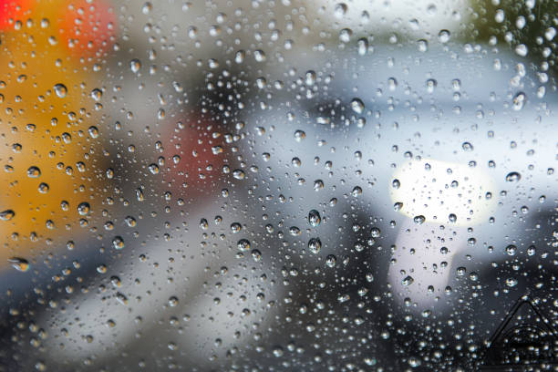 Raindrops adorn windowpane, creating a melancholic ambiance, symbolizing solitude, introspection, and nature's serene beauty on a rainy day