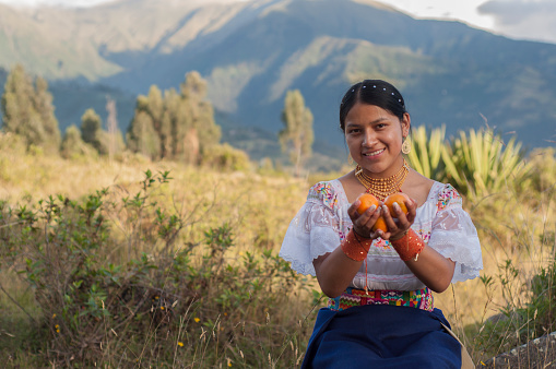 copyspace of indigenous girl smiling and showing the camera some mandarins from her orchard. High quality photo