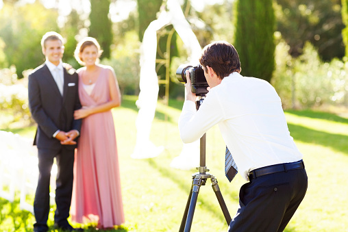 Hombre tomando acompañantes del novio y dama de honor en boda en el jardín photo