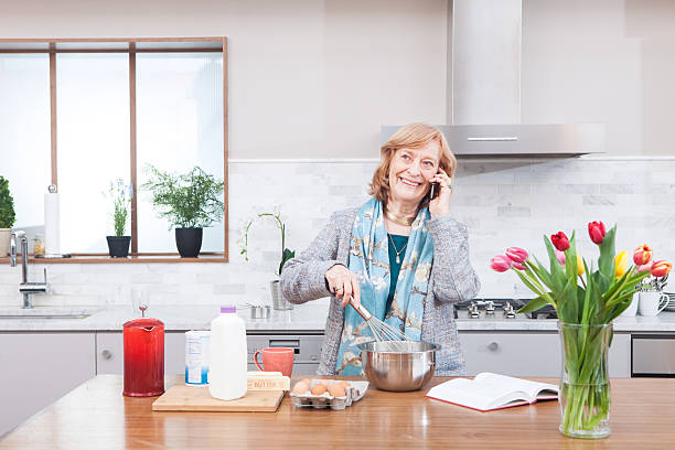 istock Smiling grandmother cooking talking on phone in kitchen 181062667