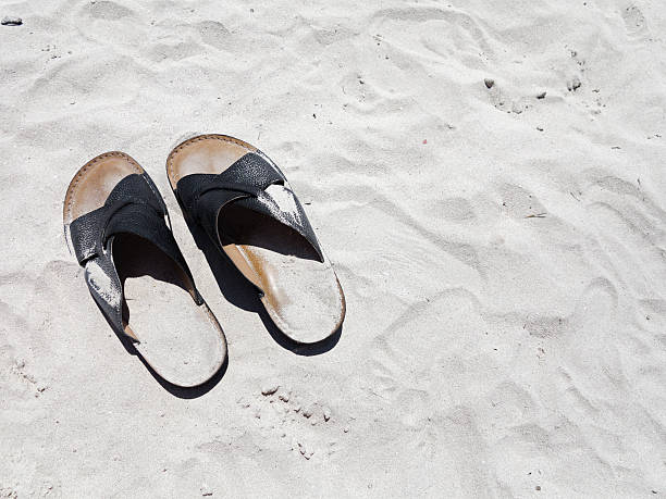istock Black leather sandals on the beach. 181062738