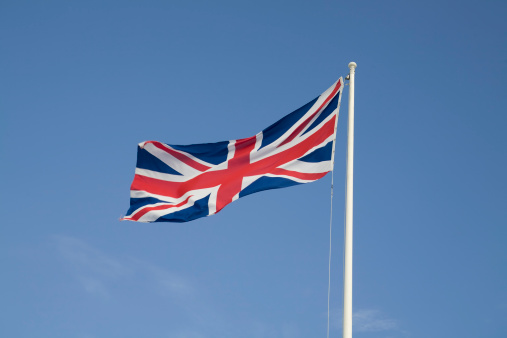 the english union jack flag flutters in the clear blue sky