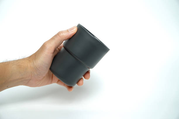 Mockup of men's hand holding a medium sized black plastic cup isolated on a white background.