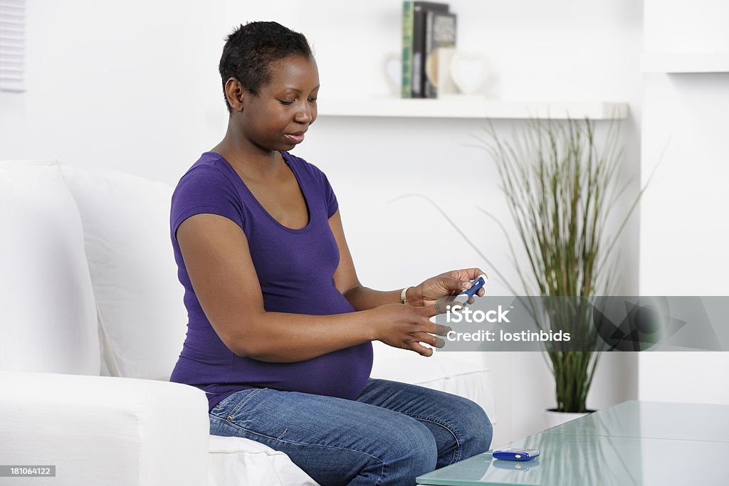 Afro-americana donna incinta il monitoraggio della glicemia a casa - Foto stock royalty-free di Diabete gestazionale
