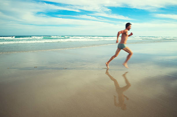 uomo in costume da bagno luminoso esegue in spiaggia tropicale - men swimming trunks beach racing briefs foto e immagini stock