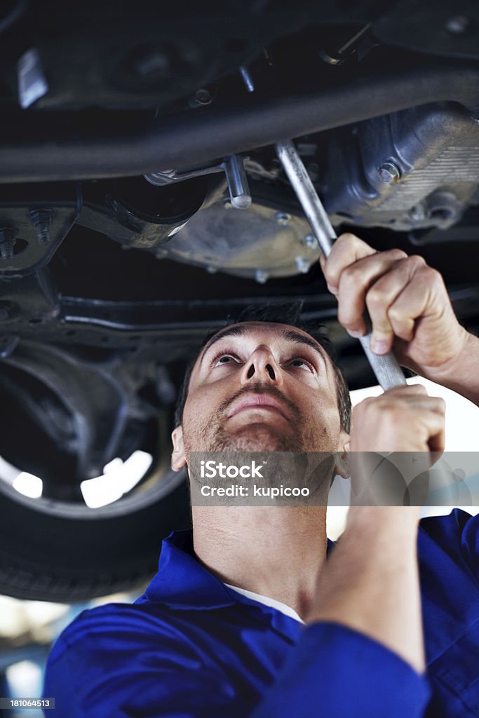 Focused on the task at hand Mechanic using a tool to make adjustments underneath a vehicle he is working on 30-39 Years Stock Photo