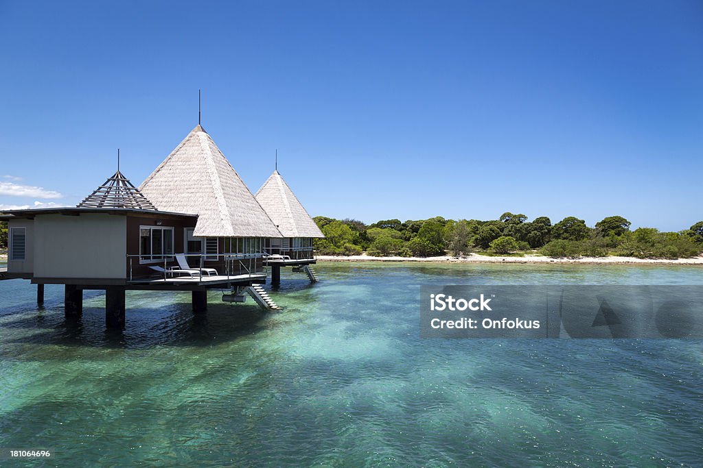 Tropical Paradise Luxury Over Water Bungalow Resort DSLR picture of a Luxury over water bungalow inside a lagoon.  The water is crystal clear and calm. The sky is clear blue with few clouds. Beach Stock Photo