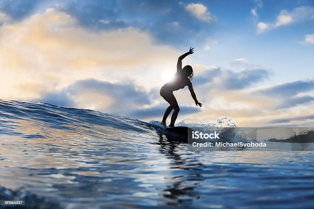 Une jeune femme blonde sur vagues de surf au coucher du soleil - Photo de Adolescence libre de droits