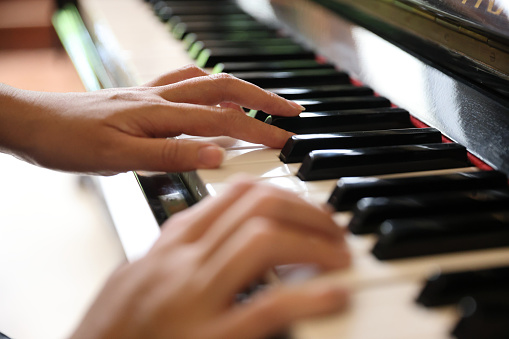 Close up of female hands playing a melody on piano