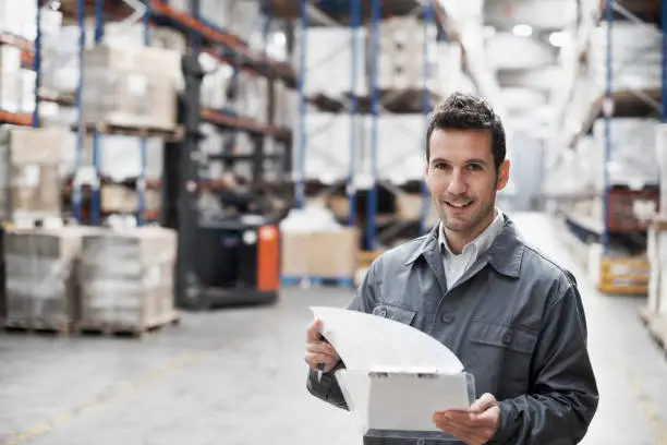 Handsome warehouse worker doing a stocktake while in a warehouse