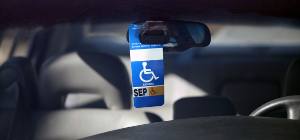 Disabled parking permit hanging in the window of a car.