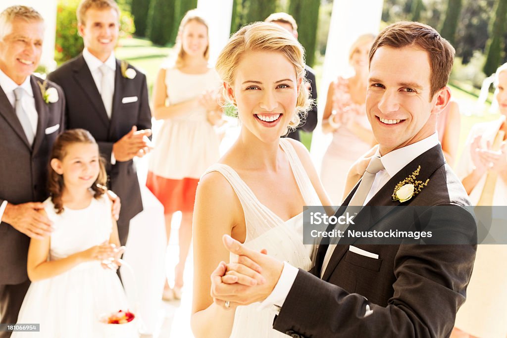 Bride and Groom Dancing With Wedding Guests Applauding In Background Portrait of happy newlywed couple dancing with wedding guests applauding in background during reception. Horizontal shot. Dancing Stock Photo