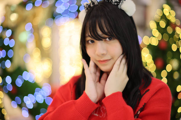 Beautiful Asian young woman with a red sweater with Christmas tree light