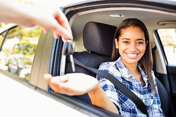 Teenage Girl Receiving Keys While Sitting In Car Portrait of happy teenage girl receiving keys while sitting in new car. Horizontal shot. teenage girls pretty smile looking at camera waist up stock pictures, royalty-free photos & images