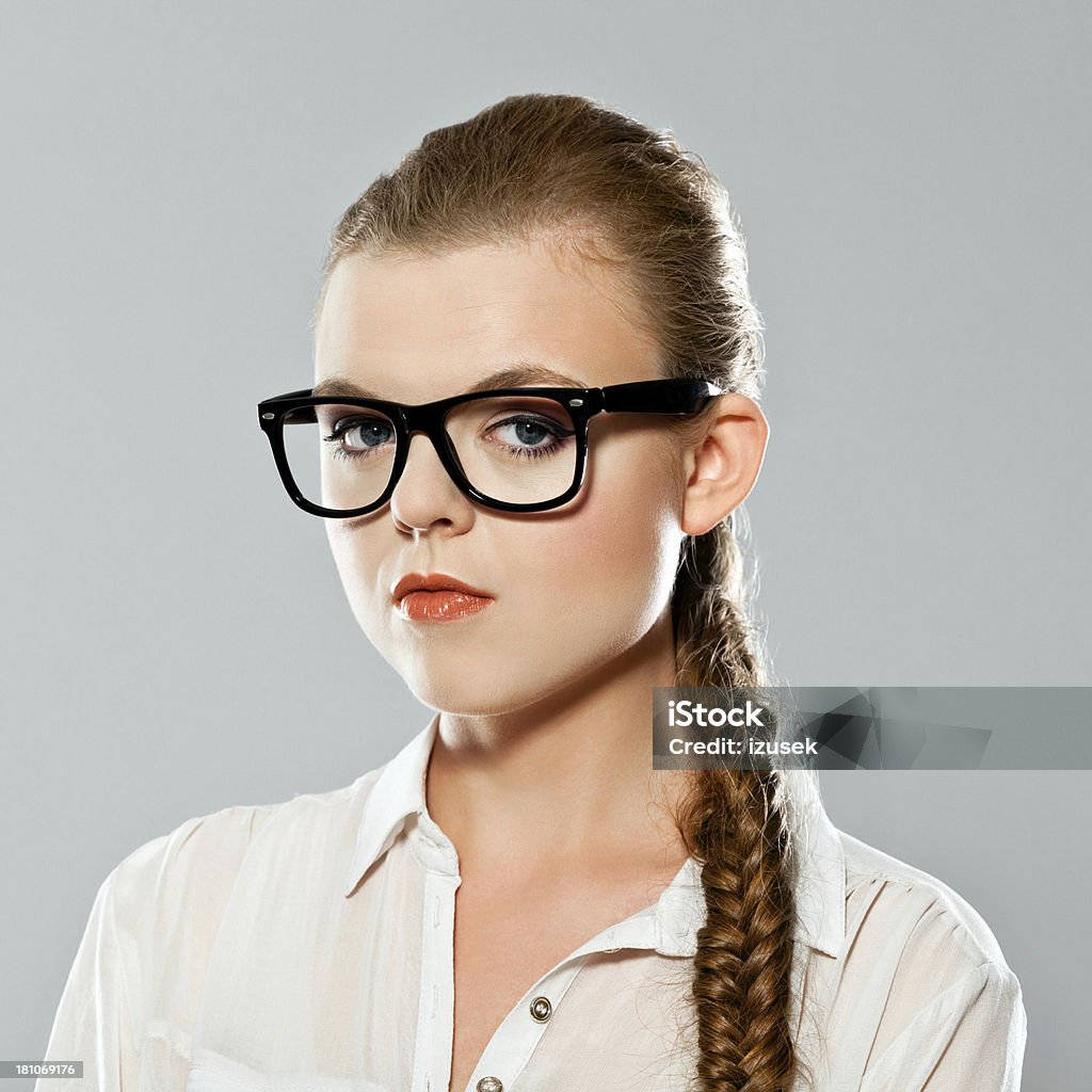 Disapproval Portrait of serious young adult woman wearing nerd glasses, looking at camera. Studio shot on grey background. 20-24 Years Stock Photo