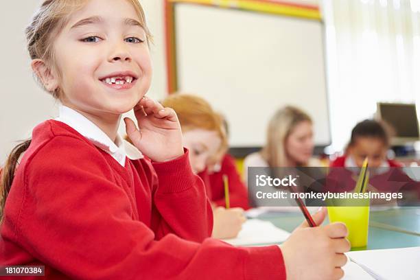 Female Elementary Pupil Working At Desk Stock Photo - Download Image Now - 6-7 Years, Adult, Book