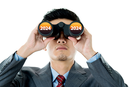 Businessman using binoculars to look at 2024
