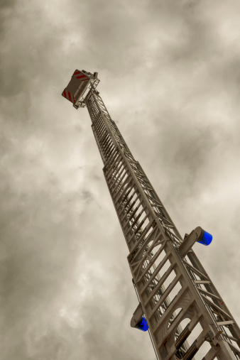 Fire ladder against dramatic sky. Toned picture.