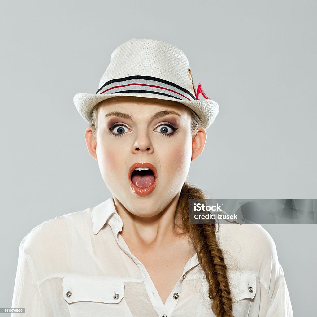 Shock Portrait of shocked young adult woman wearing hat, gasping. Studio shot on grey background. 20-24 Years Stock Photo