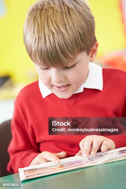 Pupil Reading Book At Table Stock Photo - Download Image Now - Boys, Reading, School Uniform