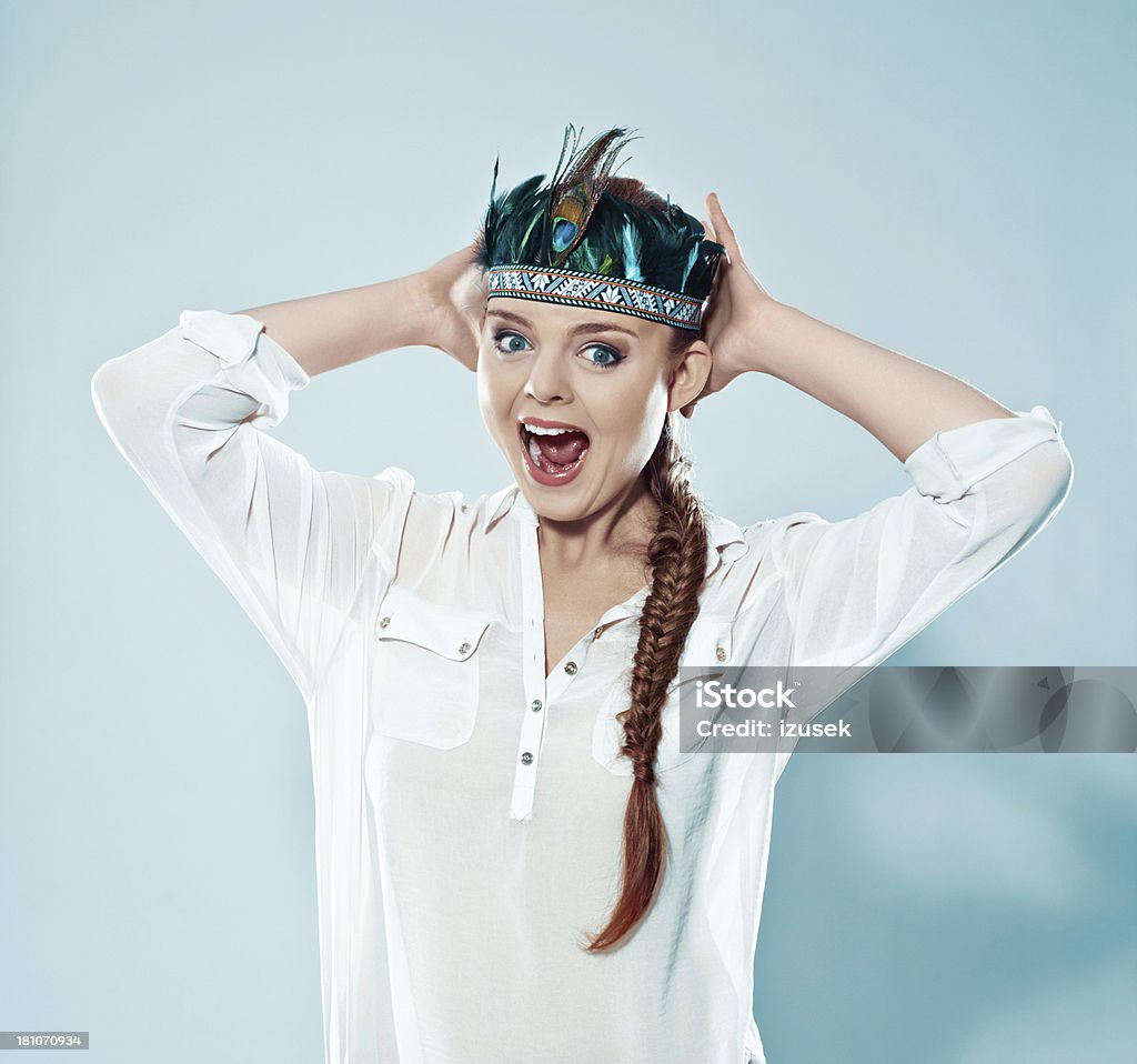 Woman wearing feather headdress Fashion portrait of young adult woman wearing feather headdress, screaming at the camera. Studio shot. 20-24 Years Stock Photo