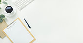 Top view office table desk workspace frame with green leaves eucalyptus, clipboard, keyboard computer and coffee cup isolated on white background. Flay lay,  ideas, notes or plan writing concept