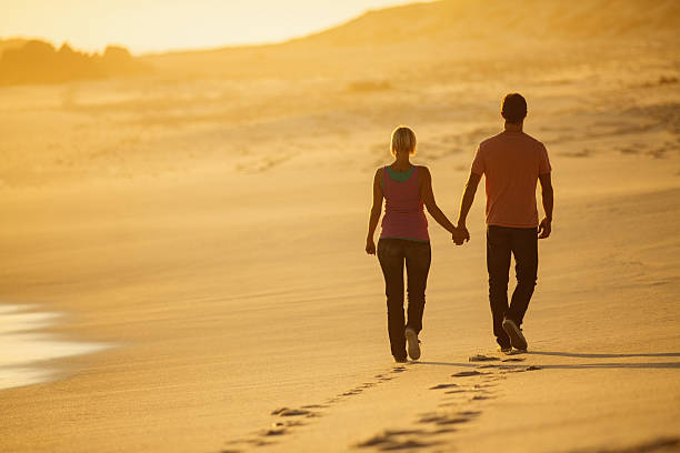 istock Couple Holding Hands While Walking On Beach At Sunset 181071228