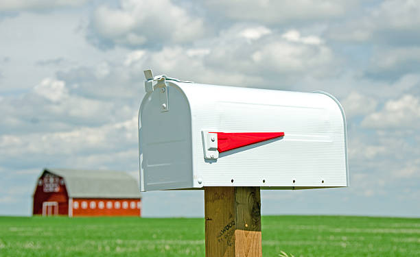 istock Closeup of white mailbox with red flag with red barn 181071679