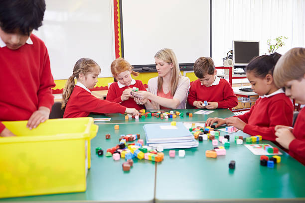 istock Pupils And Teacher Working With Coloured Blocks 181072292