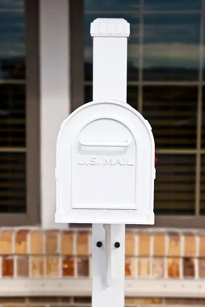 White U.S. Mailbox in front of a Store, selective focus, shallow depth of field.