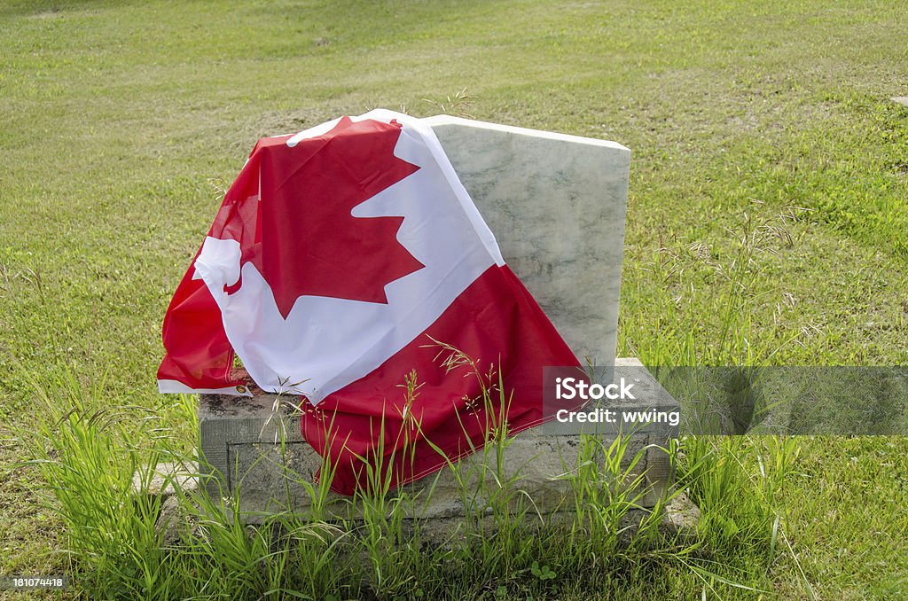 Canadian flag draped over a tombstone with green grass Canadian flag on a tombstone. Canada Stock Photo