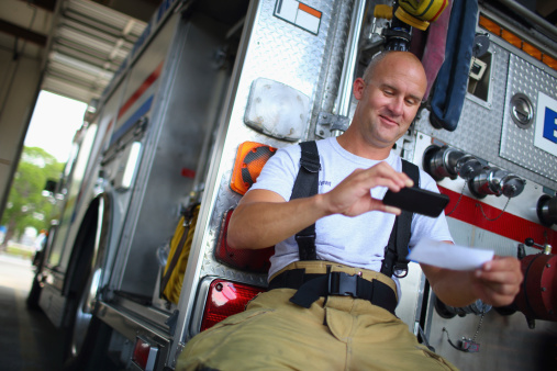 Fireman depositing check with mobile phone at the fire station