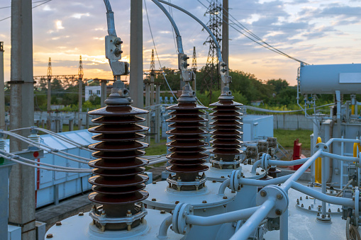 High and low voltage transformer bushings with electrical insulation and electrical equipment at a power substation.