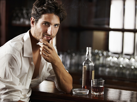 Sexy dishevelled young man smoking and drinking at the bar -  Copyspace