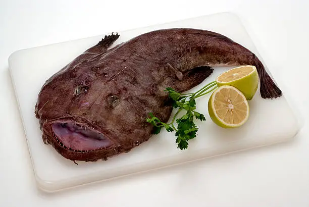 Monkfish with lemons and parsley on a plastic cutting board with clipping path